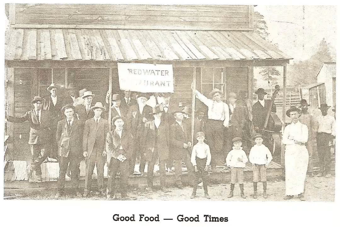 A historic group portrait outside the Redwater Restaurant, featuring men, women, and children, celebrating community and good food.