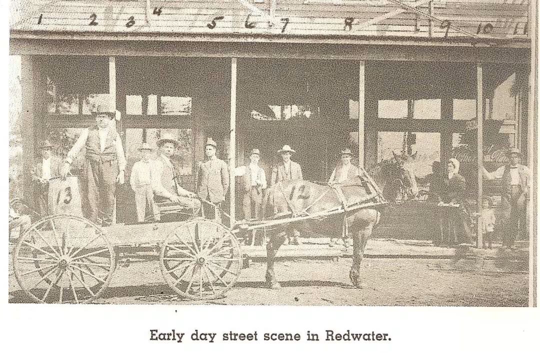 Early street scene in Redwater with a group of men and women posing around a horse-drawn wagon, showcasing vintage community life.